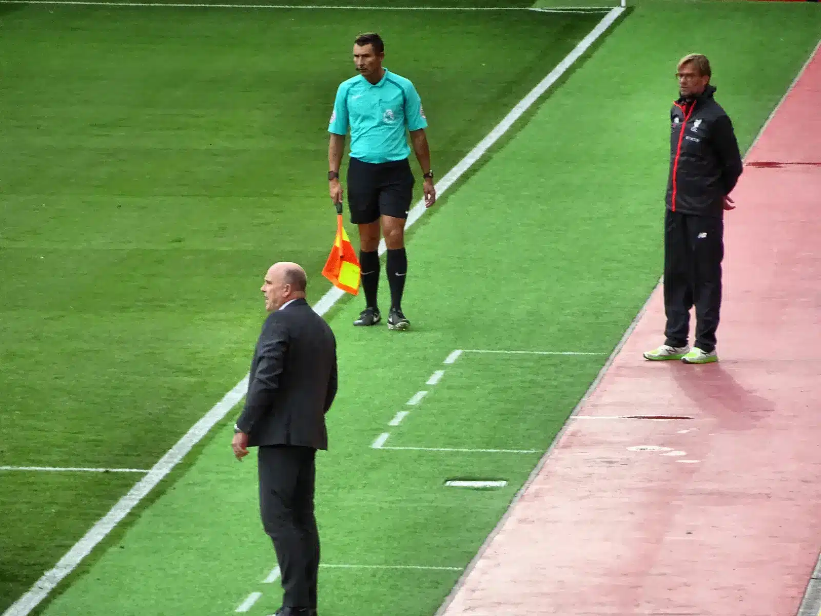 Jürgen Klopp im schwarzen Anzug am Spielfeldrand eines Fußballspiels.